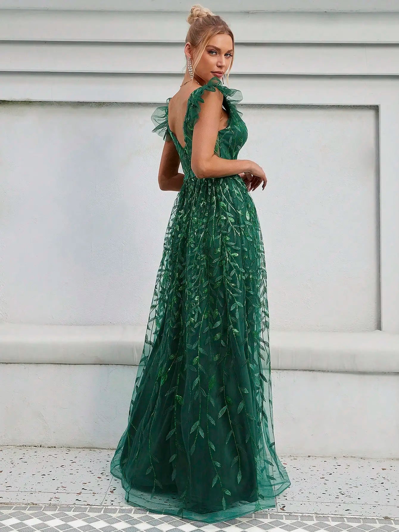 امرأة رشيقة ترتدي فستانًا أخضر منقوشًا بأوراق الشجر